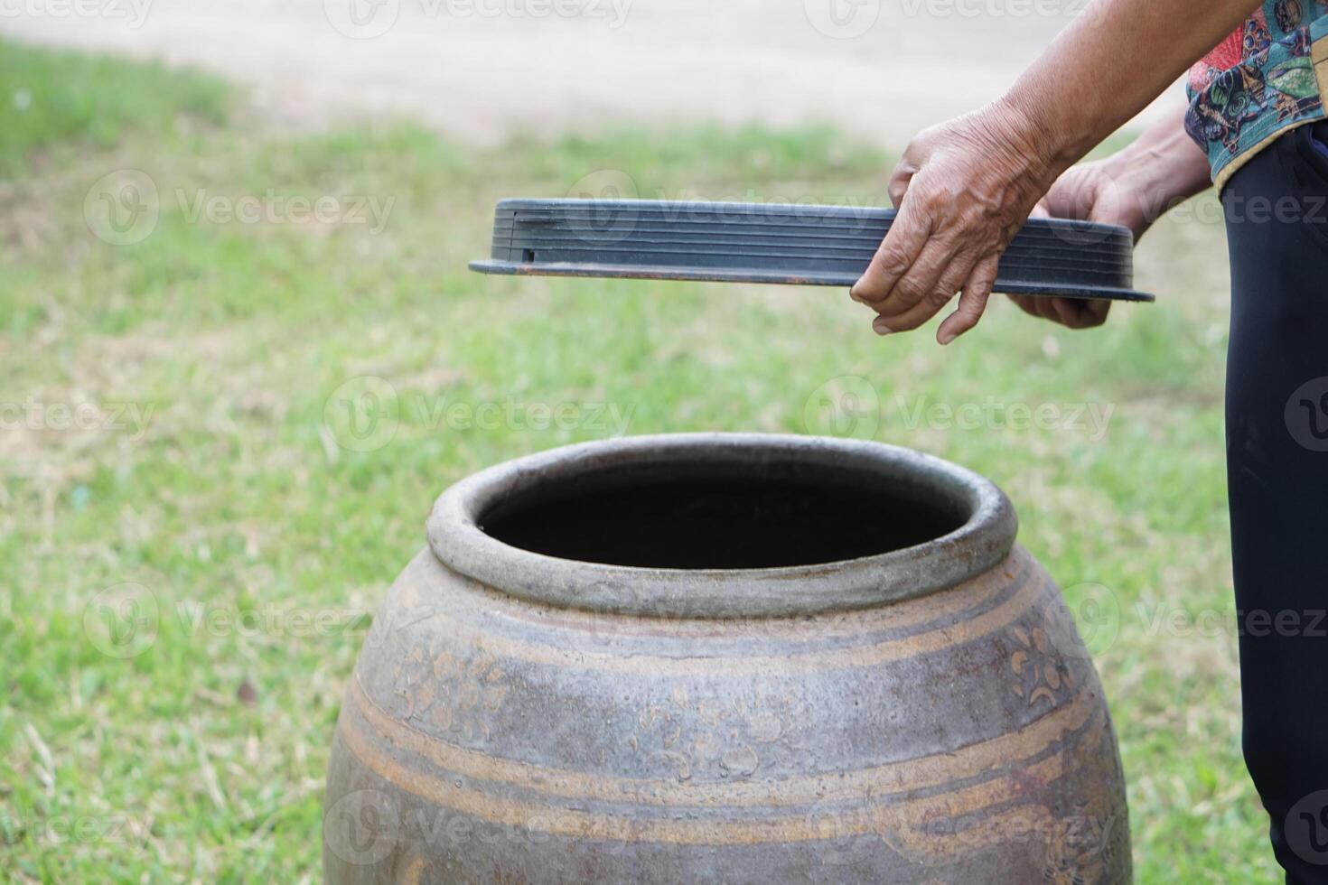 Closeup hands hold lid to cover water jar to protect from mosquitoes to breed inside or other  insects or dust go into water. Concept, campaign to stop mosquitoes cycle to lay eggs in water container photo