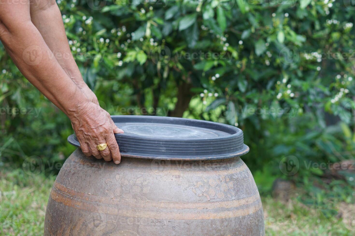 Closeup hands hold lid to cover water jar to protect from mosquitoes to breed inside or other  insects or dust go into water. Concept, campaign to stop mosquitoes cycle to lay eggs in water container photo