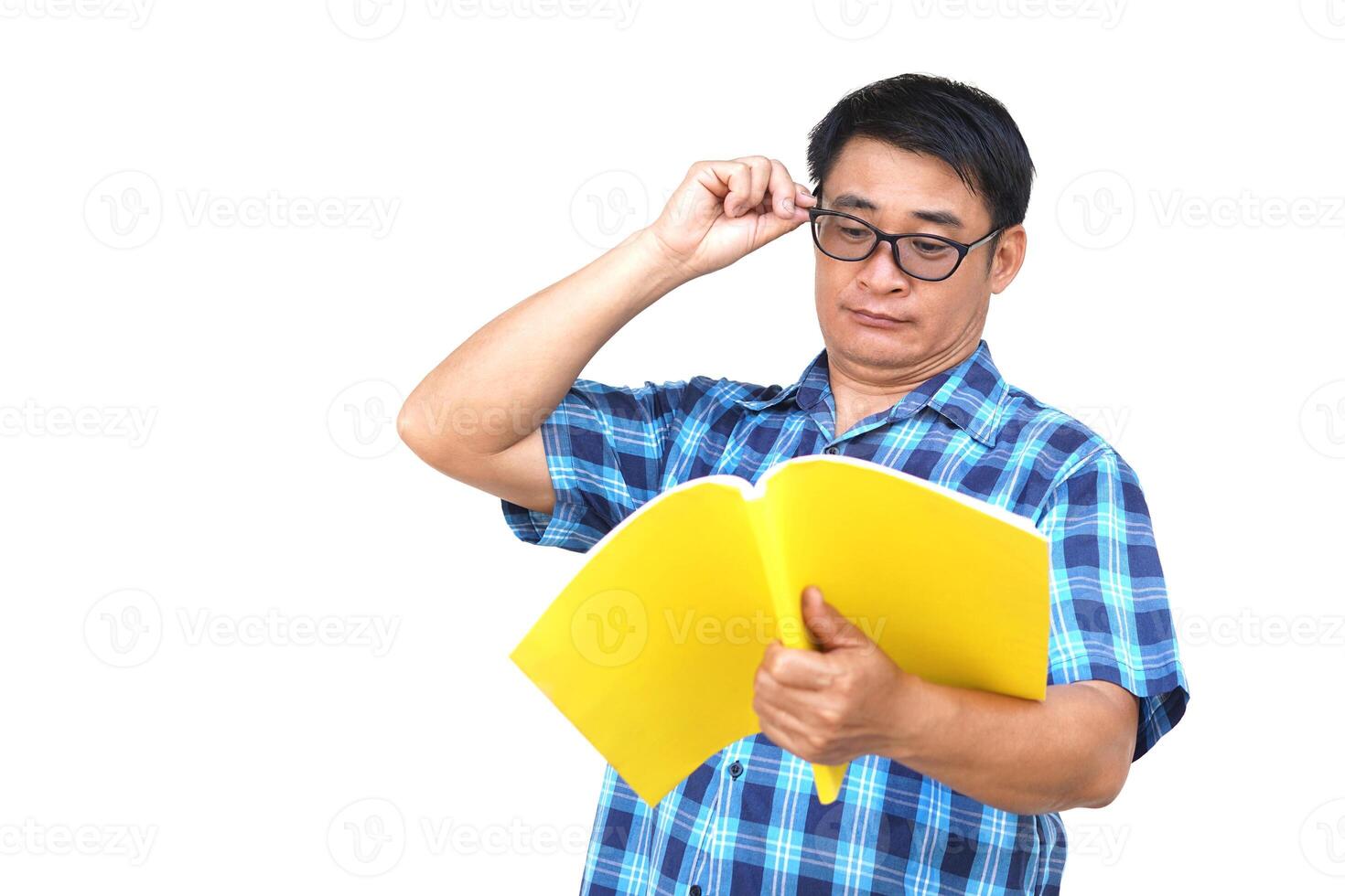 Asian  man wear blue shirt, eyeglasses, holds book to read, isolated on white background. Concept , reading for knowledge or pleasure. Hobby and relax time. Far eyesighted man is reading book. photo