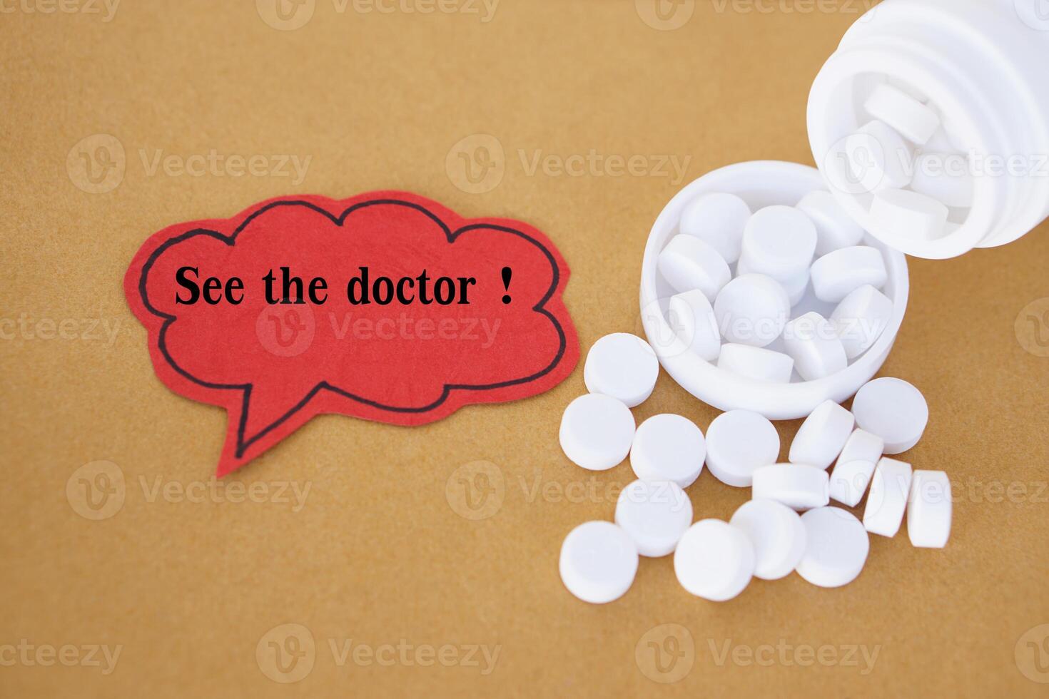 Red paper card, bubble speech with text See the doctor. Blurred white pills medicines. Concept, health care. Medical, Pharmacy. Using under doctor prescription for safety. Relief pain, ache, fever. photo