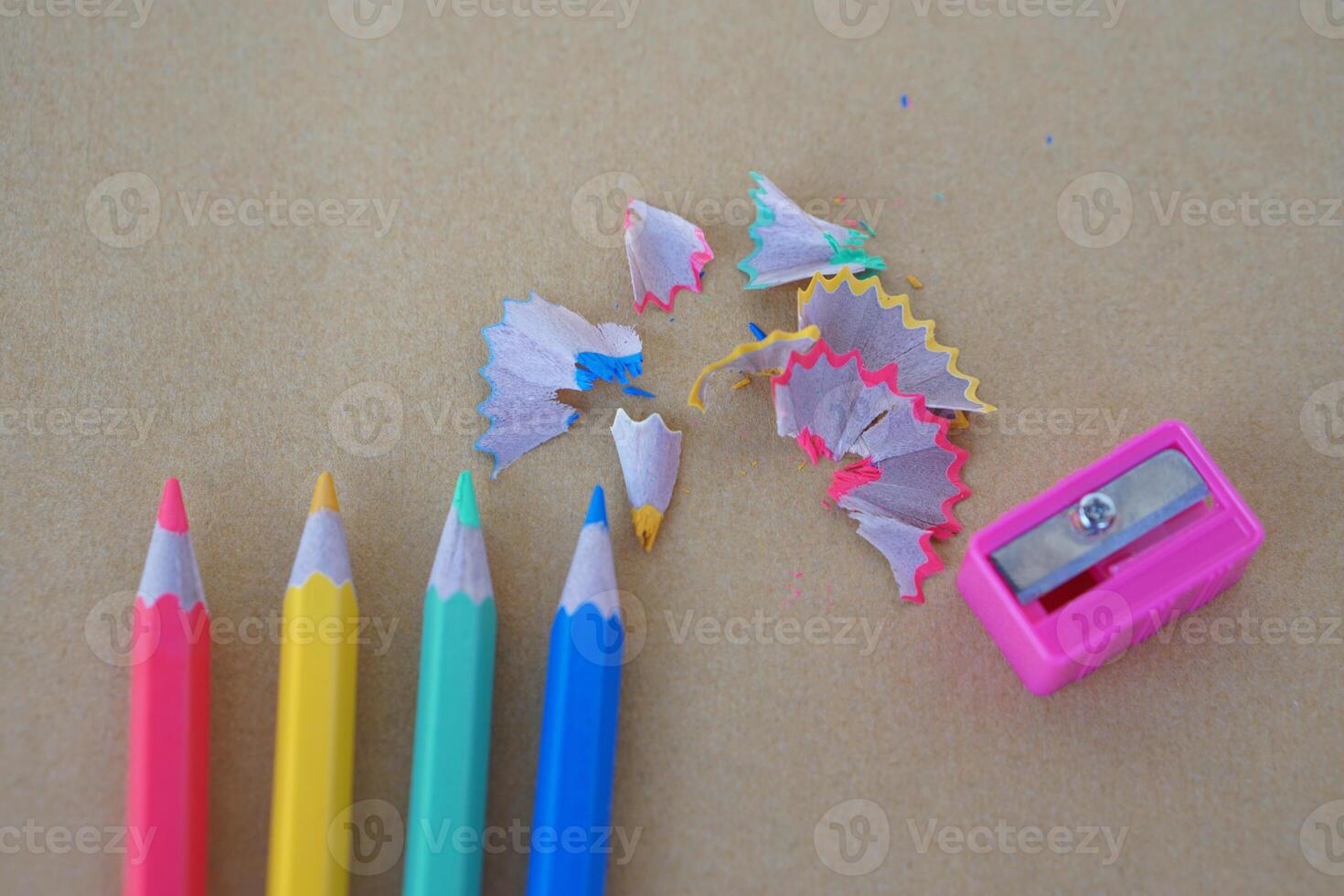Wooden colorful pencil scraps, pencils and sharpener on brown background. Concept, education materials for creative drawing, art subject, support learning of autistic disorder children photo