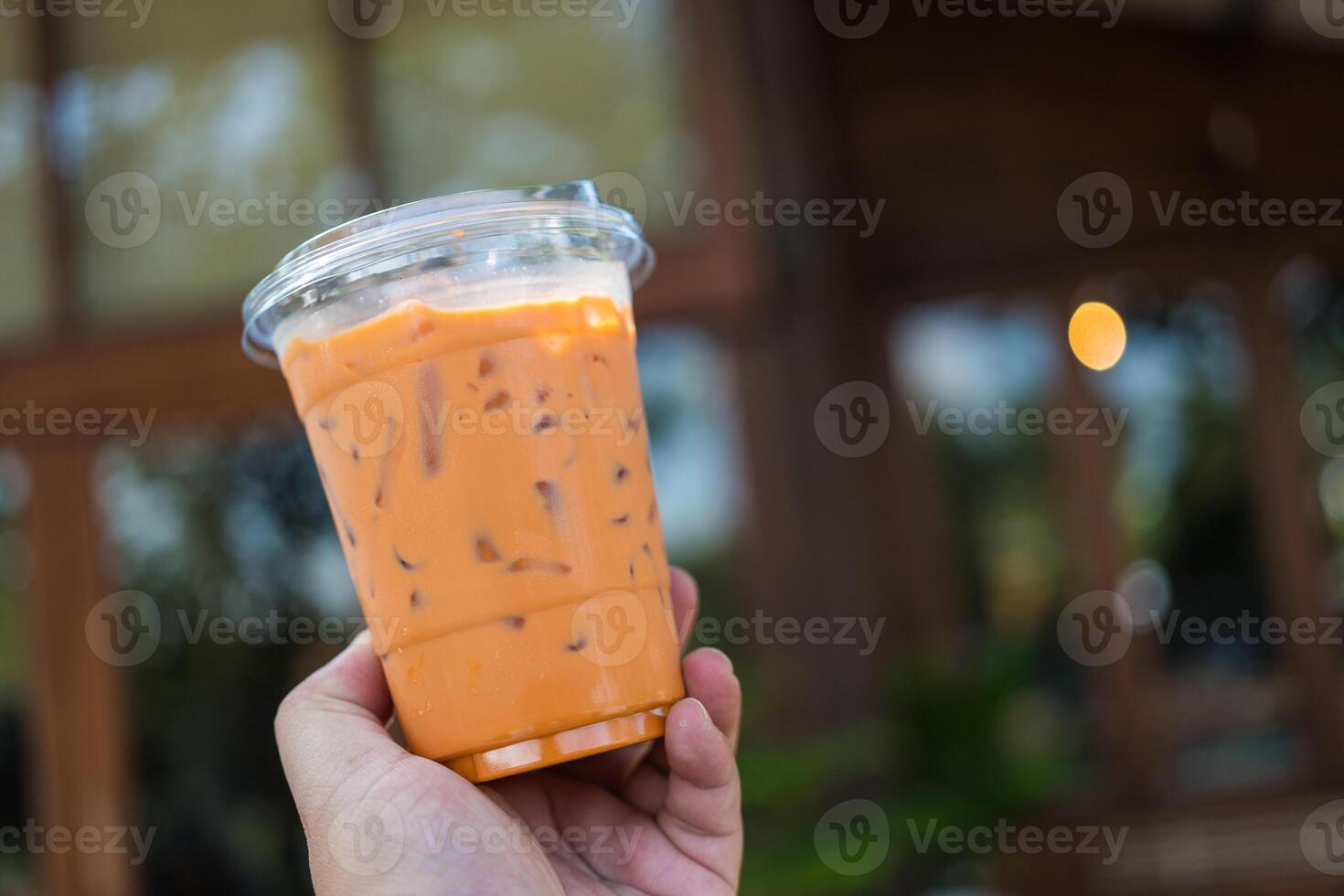 Man holding a plastic cup of iced Thai milk tea photo