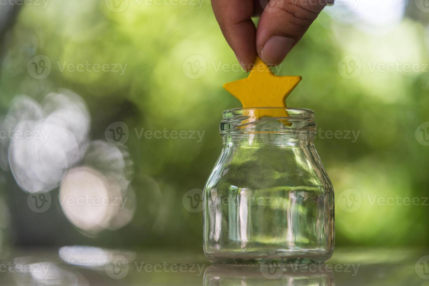 A hand put yellow star to a glass jar for vote or satisfaction service. photo