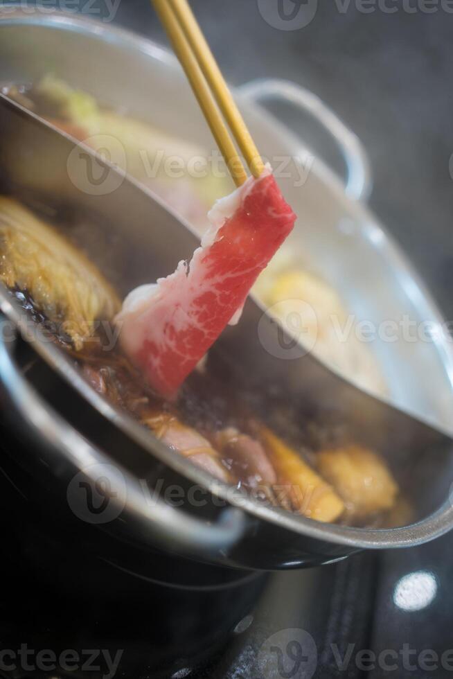 Use wood chopsticks of raw beef put to hot boiling pot Shabu shabu photo
