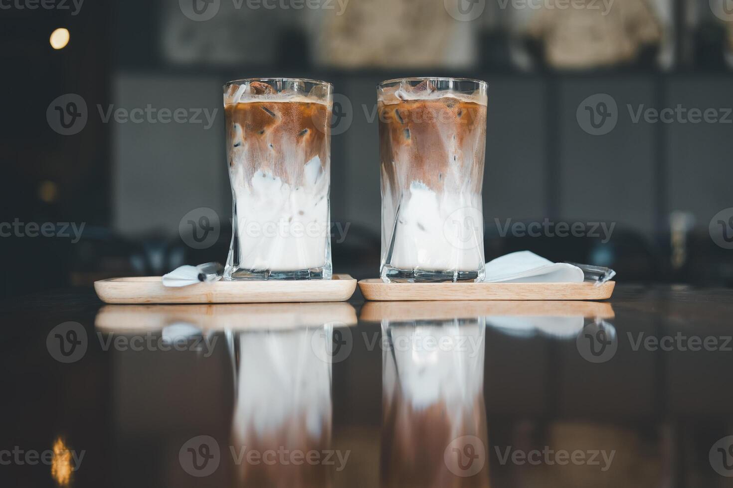 Two iced Mocha coffee two layers fresh milk and espresso short on wooden table at cafe. photo