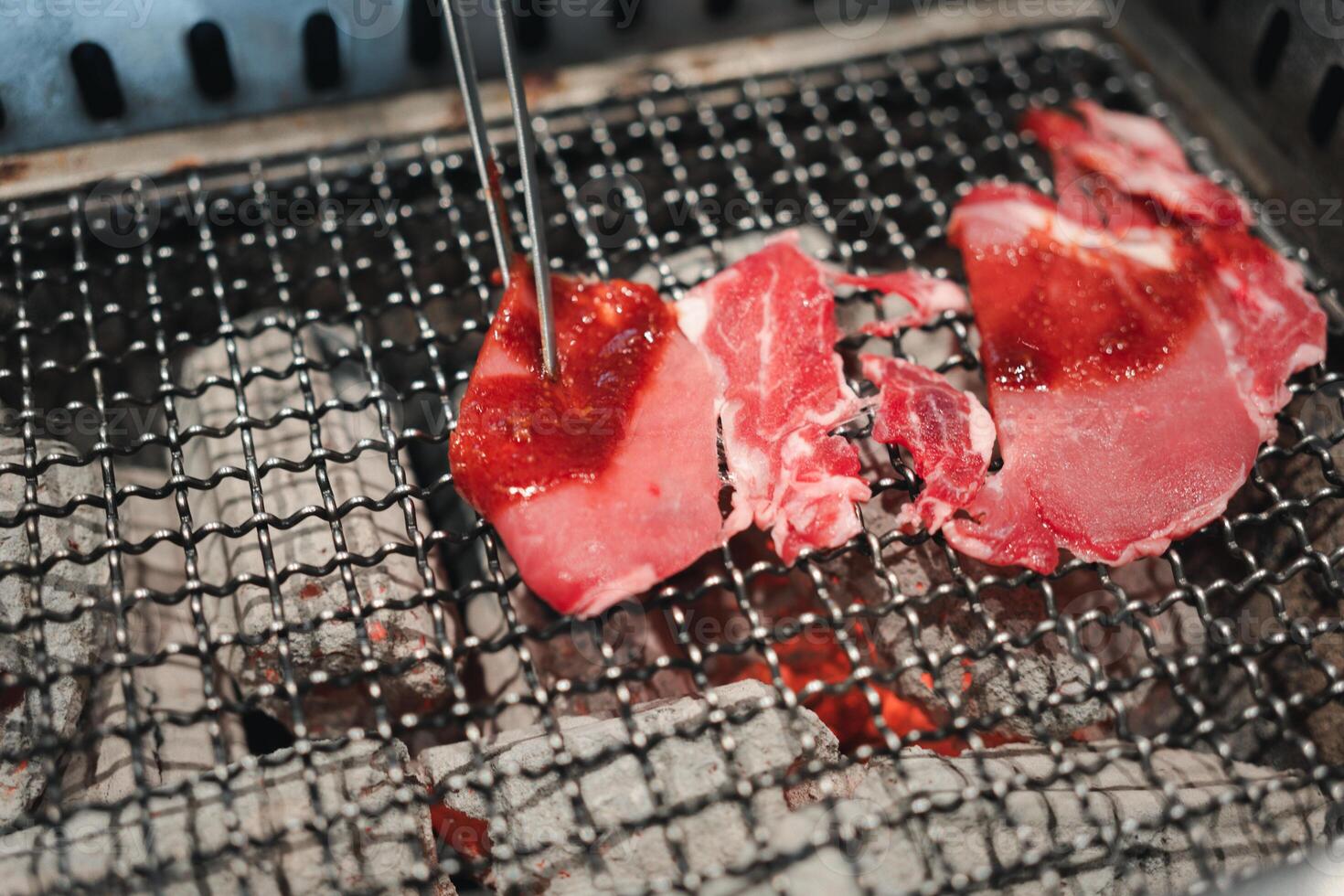 Raw beef slice grilling on fire over charcoal photo