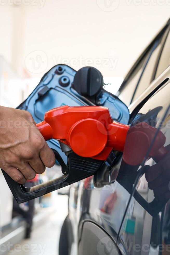 Refueling car with gasoline at gas station. Man hand grips a gasoline fuel nozzle at the refuel gas station station. photo