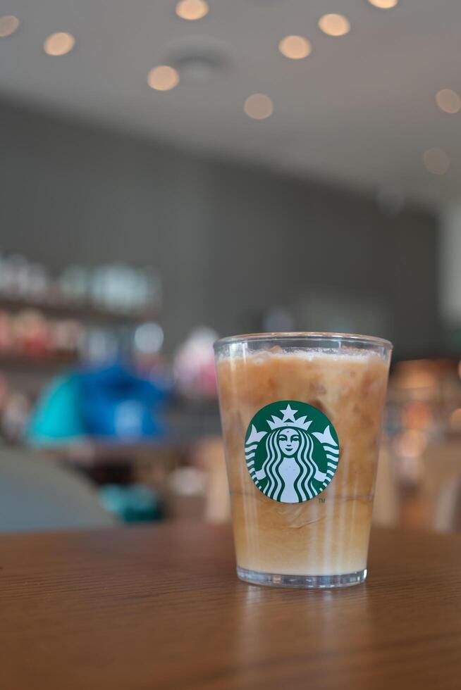 Bangkok, Thailand - January 13, 2024 Coffee refresher beverage served on crystal glass with Starbucks logo against coffee shop blur background. photo