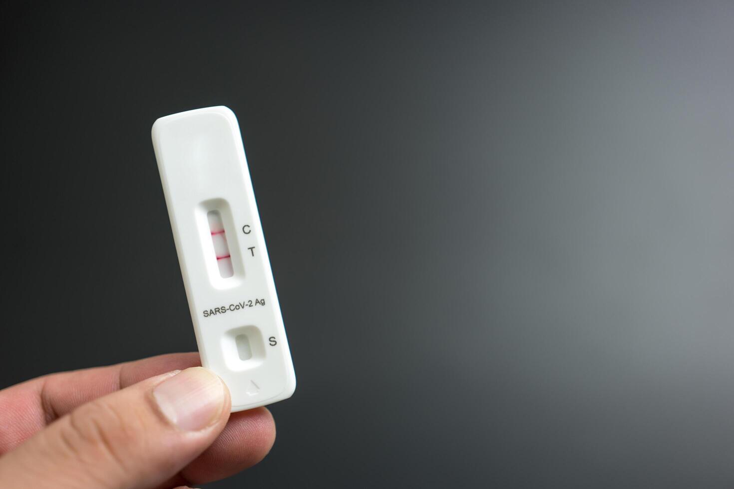 Hand showing covid-19 positive test on antigen rapid test kit for coronavirus. photo