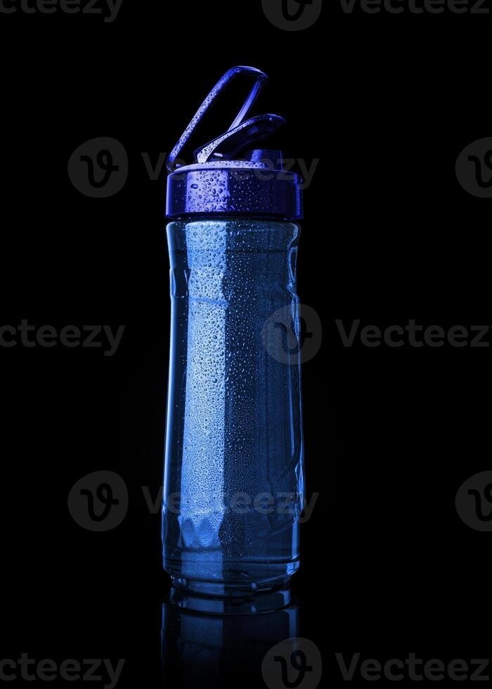 Plastic blue sports bottle is covered with droplets photo