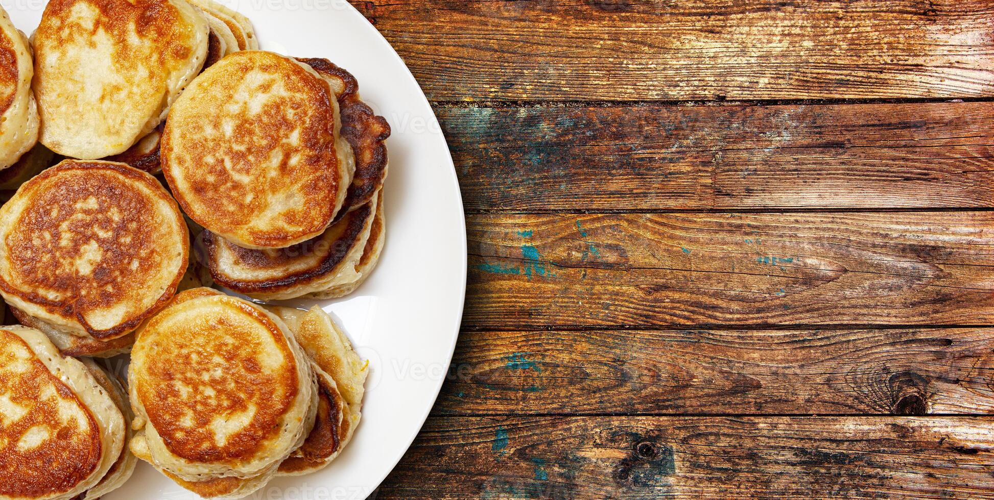 pile of freshly baked pancakes lay on a plate isolated on wooden table background. photo