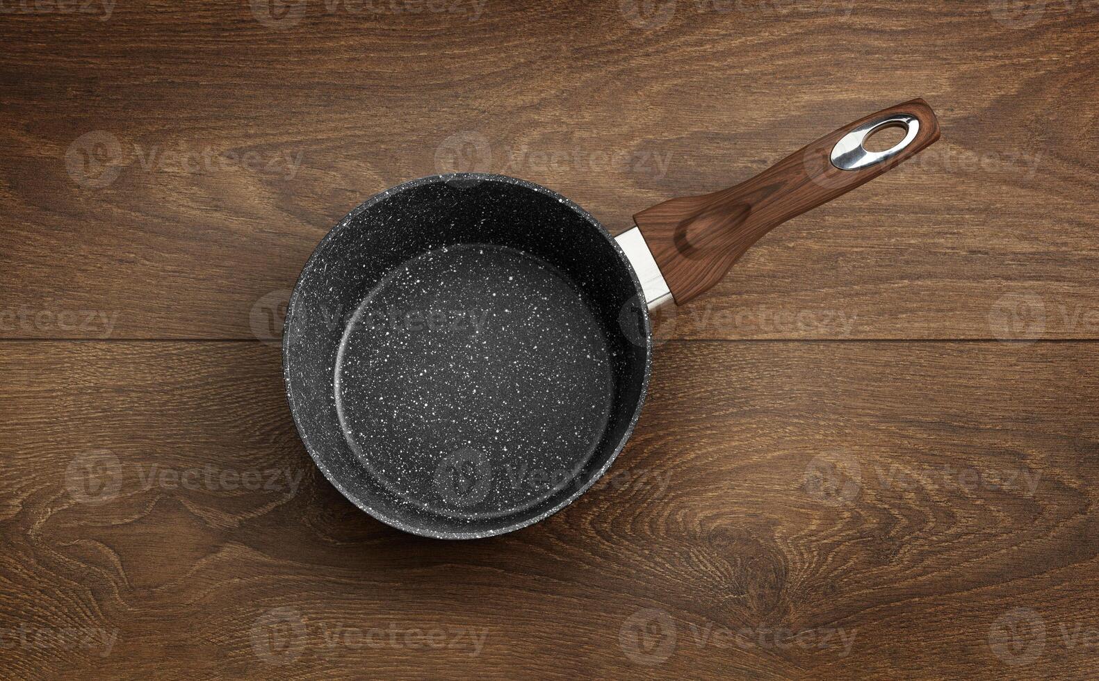 Frying pan with non-stick granite coating isolated on a wooden photo