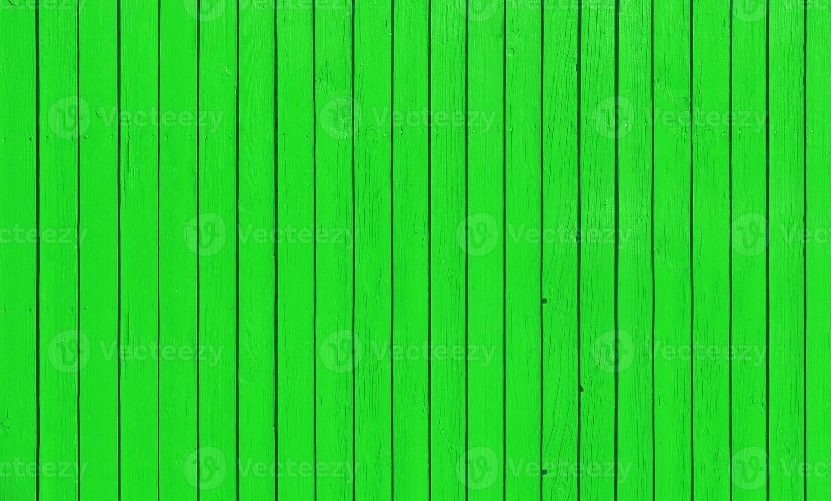 Wooden fence with parallel planks with green paint. photo