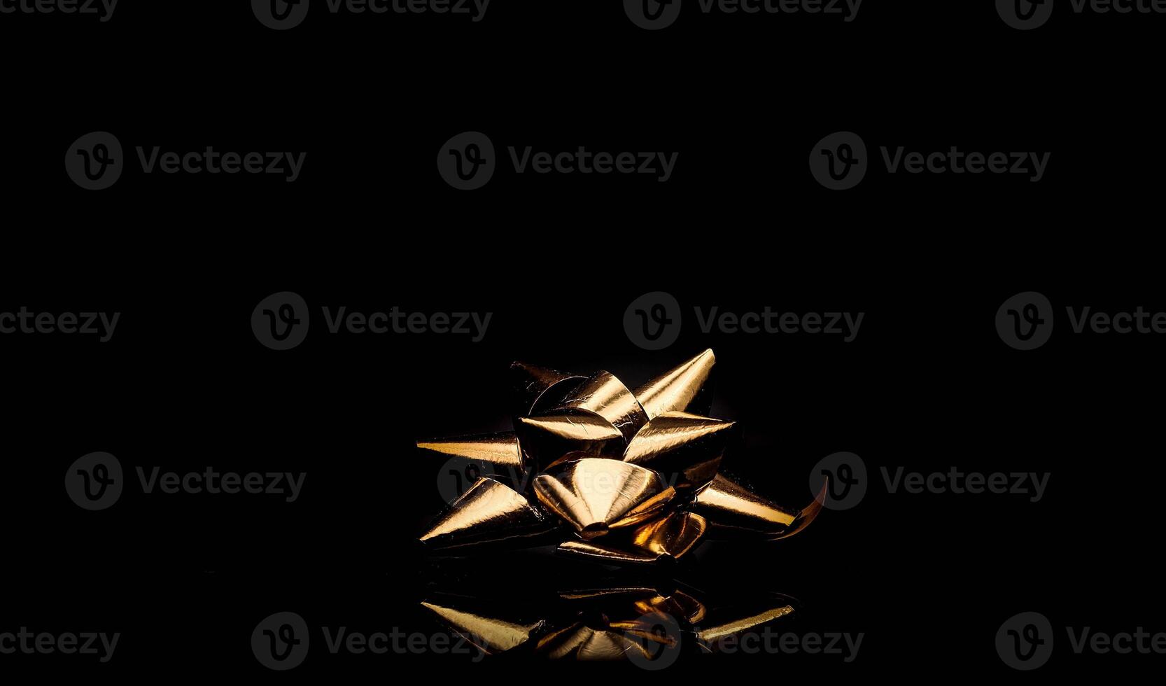 gold colored bow for gift packages on black background with photo studio lights
