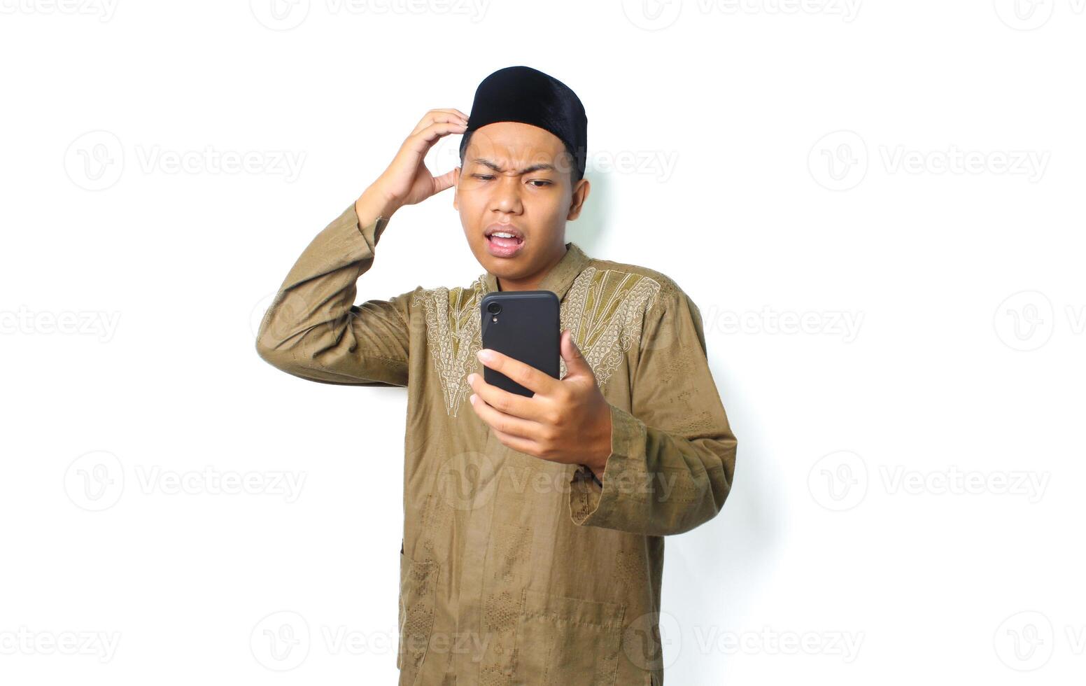 confused asian muslim man holding mobile phone with touching his head isolated on white background photo