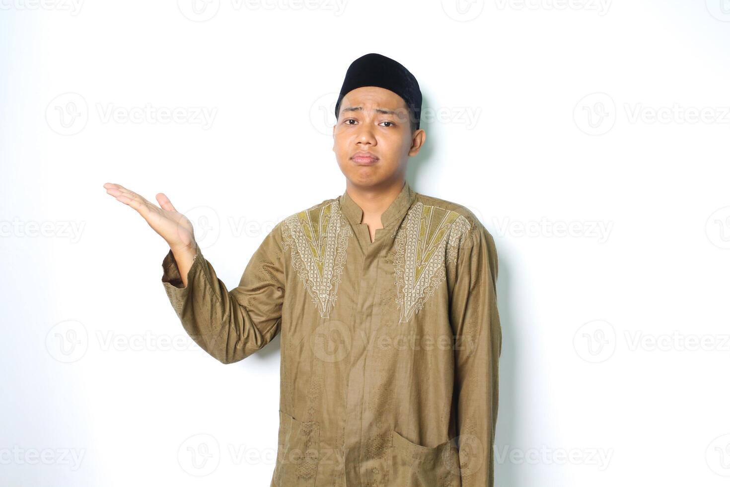 asian muslim man presenting to beside with stressed expression isolated on white background photo