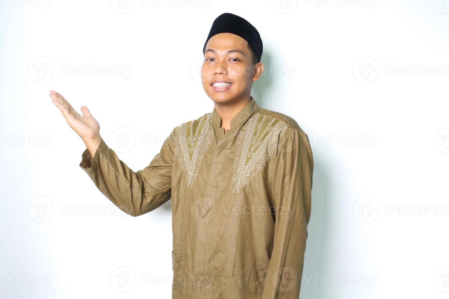 side view of smiling asian muslim man wearing islamic dress presenting empty space isolated on white background photo