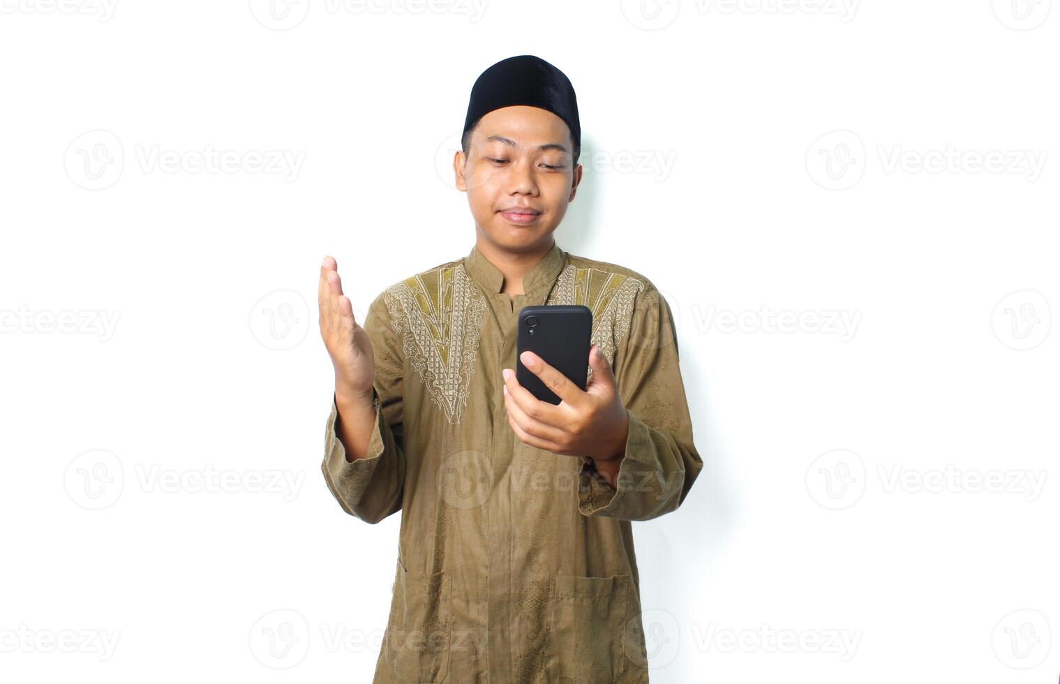 calm asian moslem man raising hand to praying when read message using mobile phone isolated on white background photo