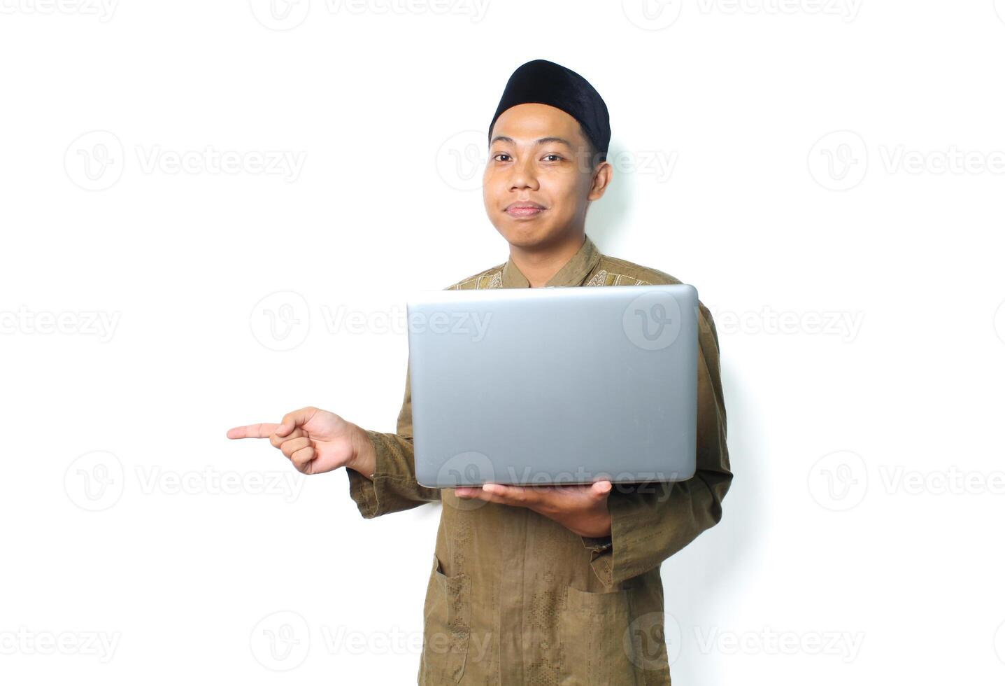 calm peaceful asian muslim man holding laptop pointing to beside isolated on white background photo