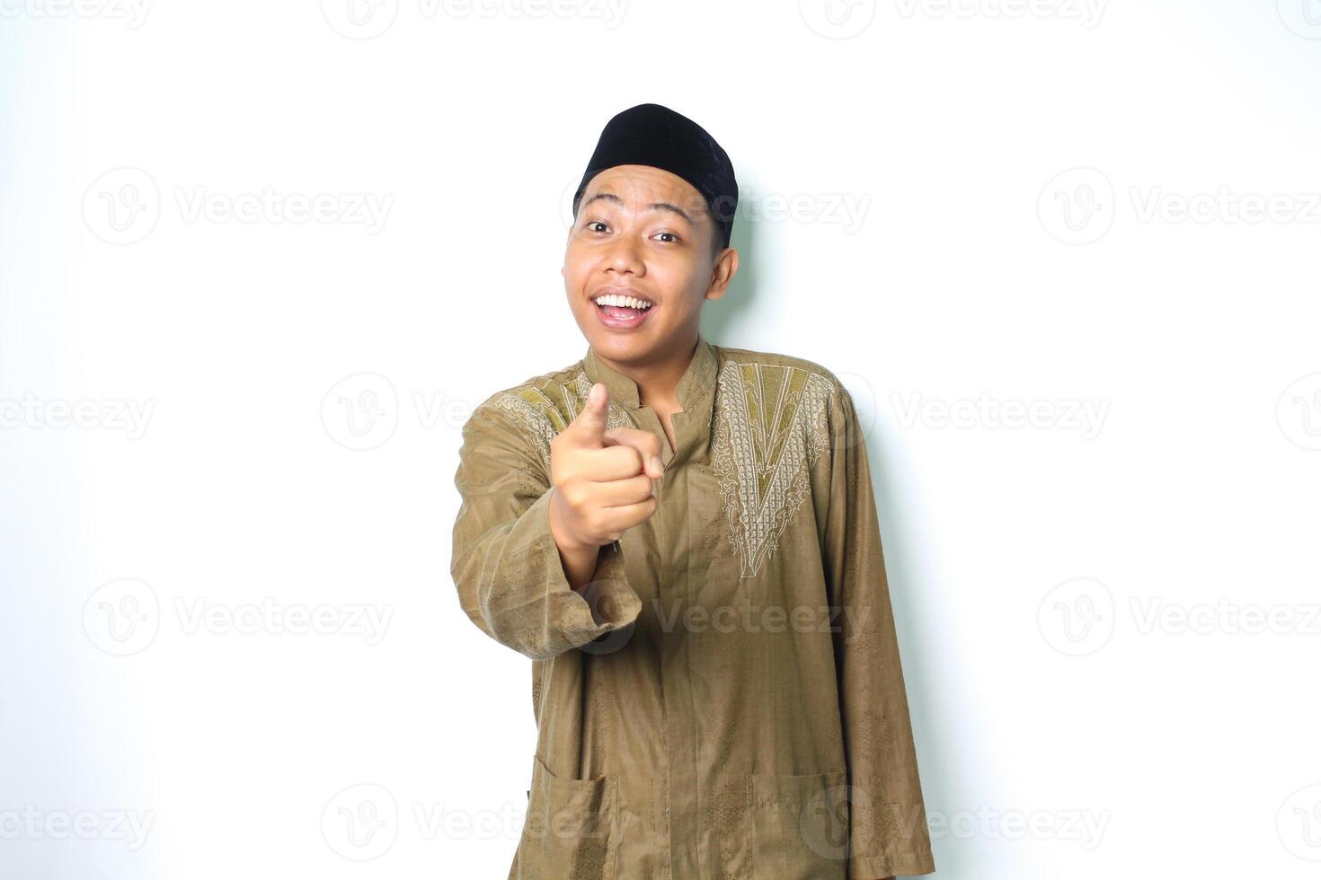 surprised asian muslim man wearing islamic clothes pointing at camera isolated in white background photo