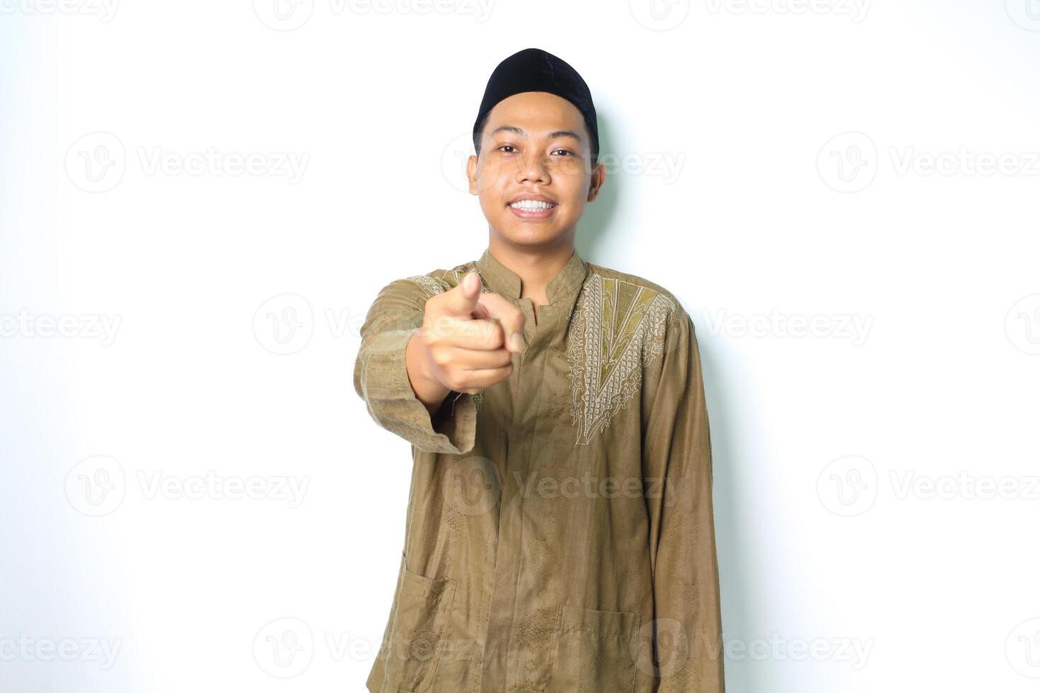 smiling asian muslim man wearing koko clothes pointing at camera with excitement isolated on white background photo