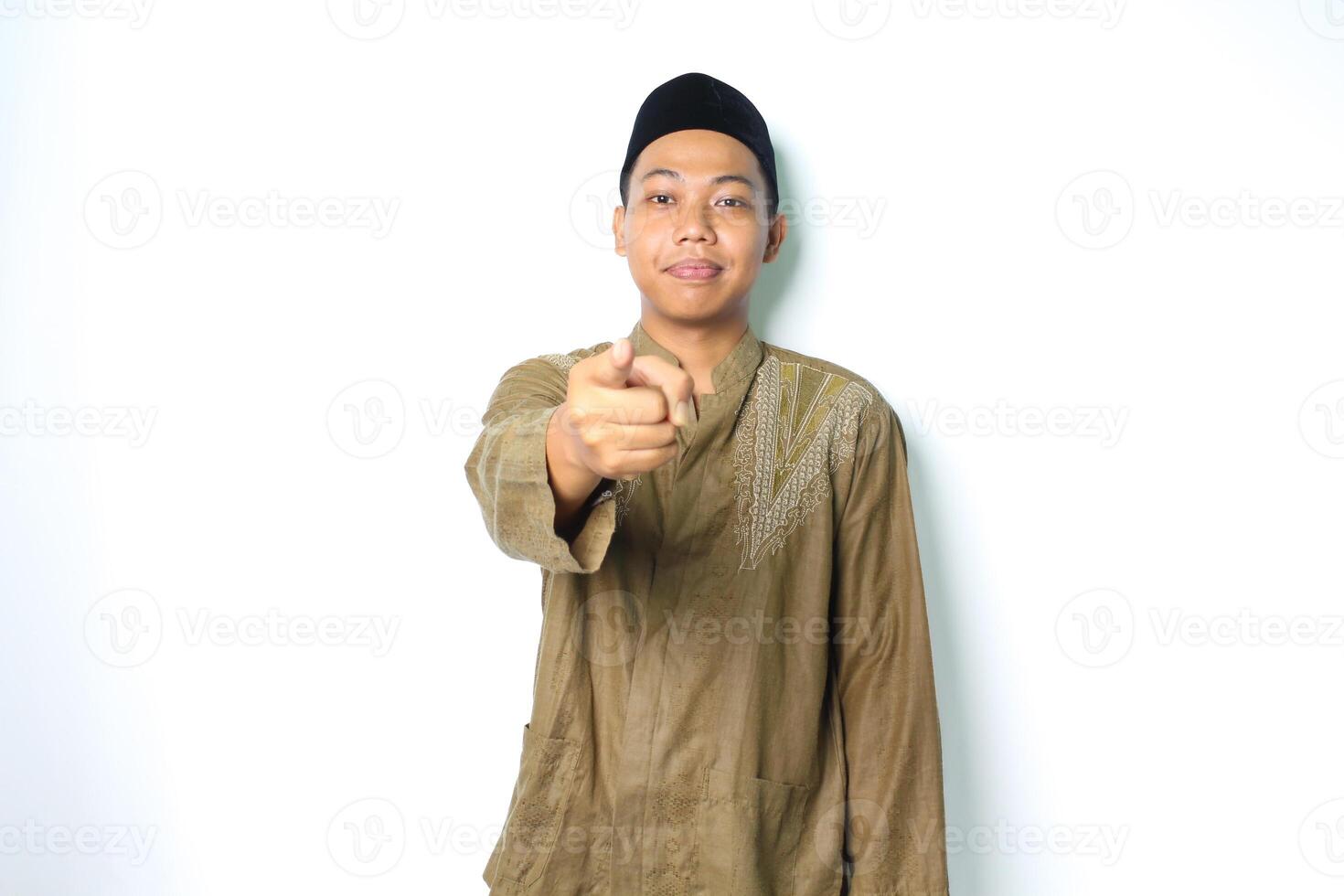 calma asiático musulmán hombre sonriente vistiendo koko ropa señalando a cámara aislado en blanco antecedentes foto