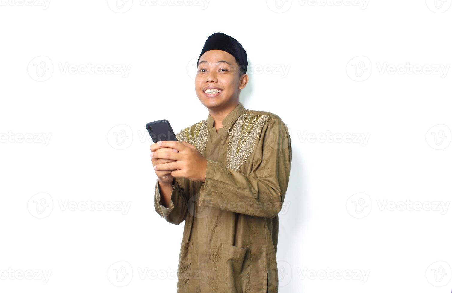 happy asian muslim man surfing in cyberspace using mobile phone isolated on white background photo