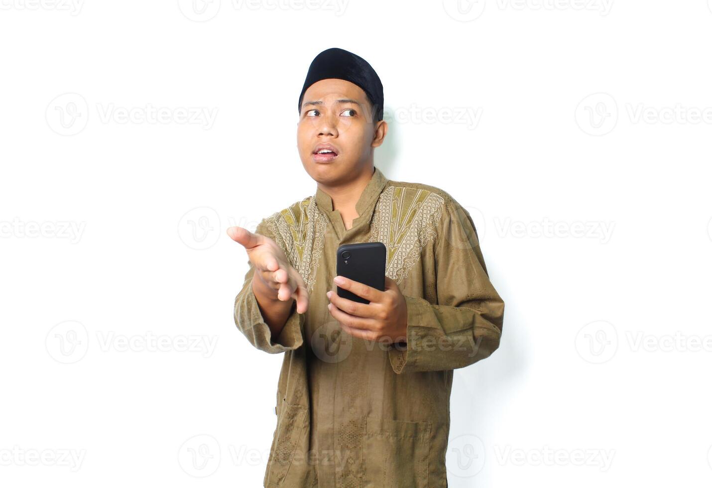 confused asian muslim man holding mobile phone offering handshake isolated on white background photo