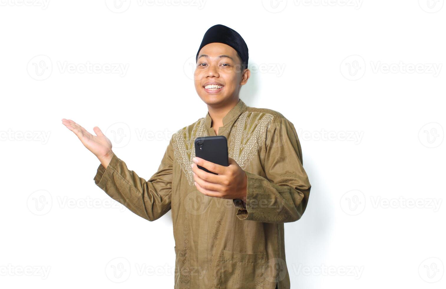 excited asian muslim man presenting to the right side with holding mobile phone isolated on white background photo
