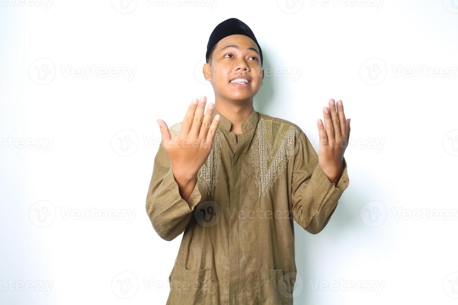 smiling asian moslem man wearing islamic clothes praying in ramadhan isolated on white background photo