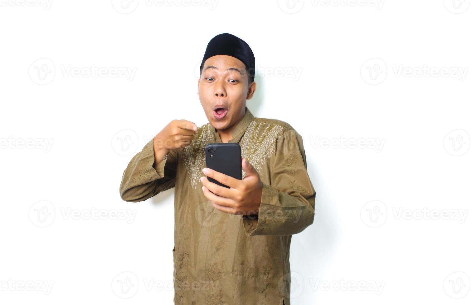 shocked asian muslim man pointing to mobile phone isolated on white background photo