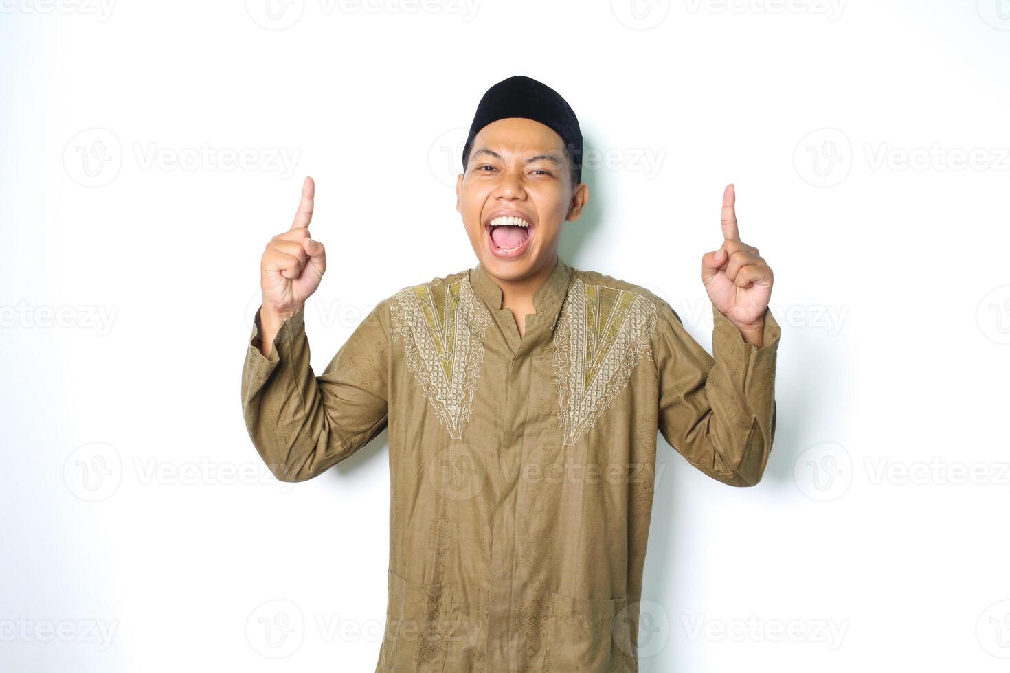 excited asian moslem man screaming with pointing to above wearing islamic dress isolated on white background photo