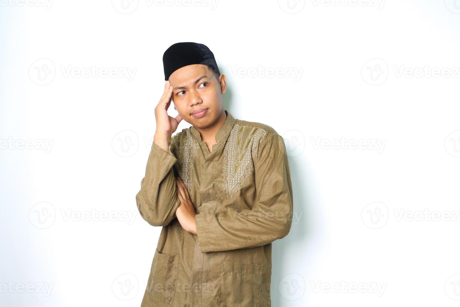 thoughtful asian muslim man thinking seriously with touching his head wearing koko clothes isolated on white background photo