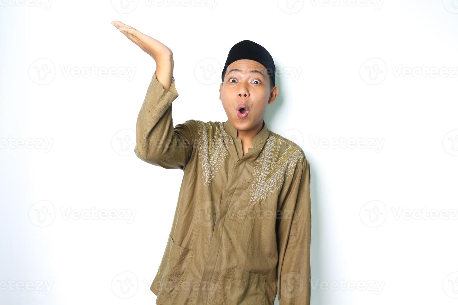 surprised asian muslim man presenting to above with open palm isolated on white background photo