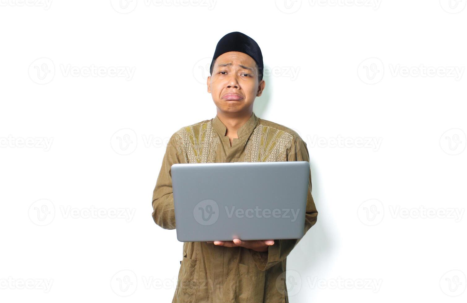 sad asian muslim man holding laptop with crying expression isolated on white background photo