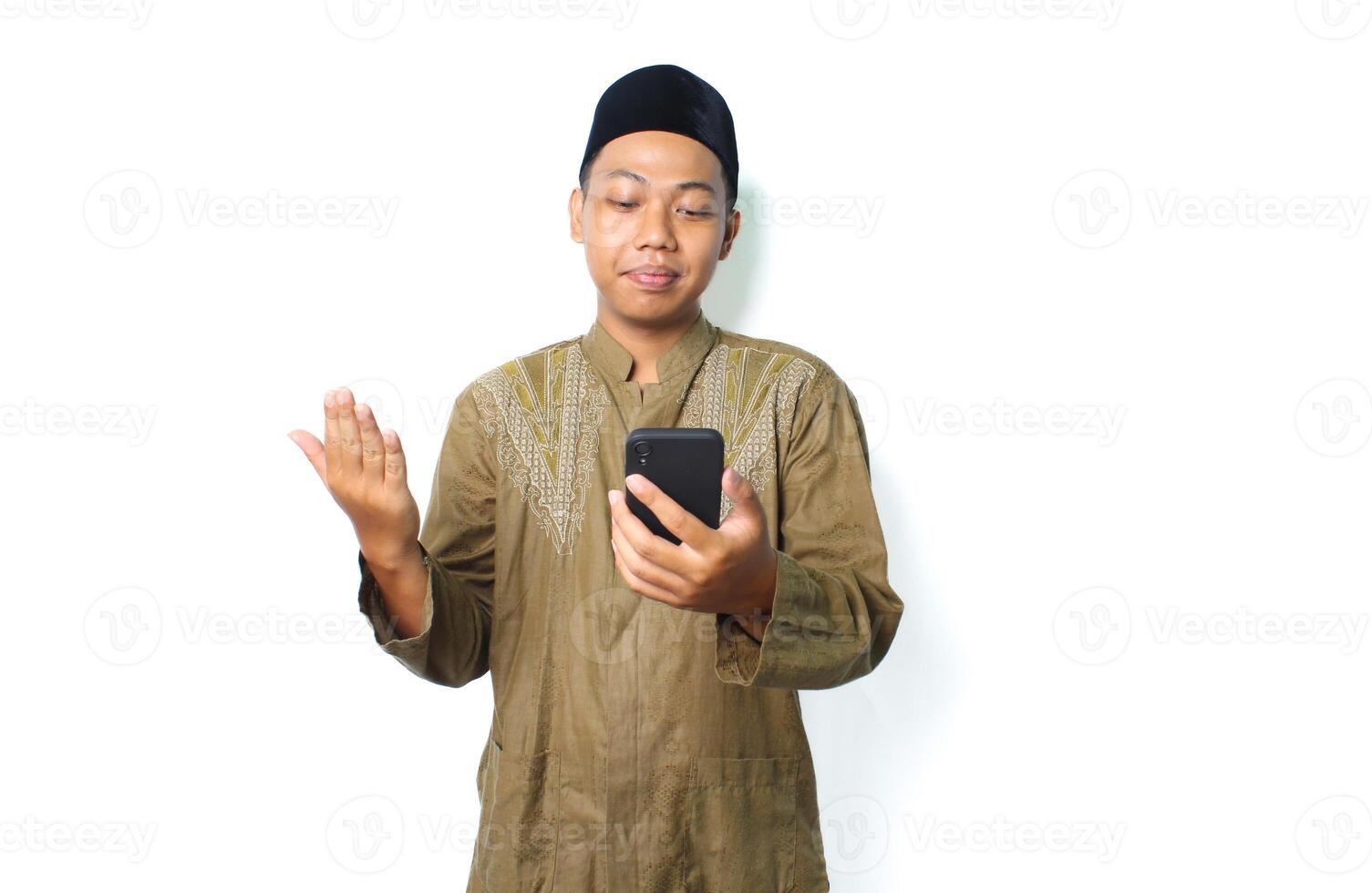 calm asian moslem man raising hand to praying when read message using mobile phone isolated on white background photo