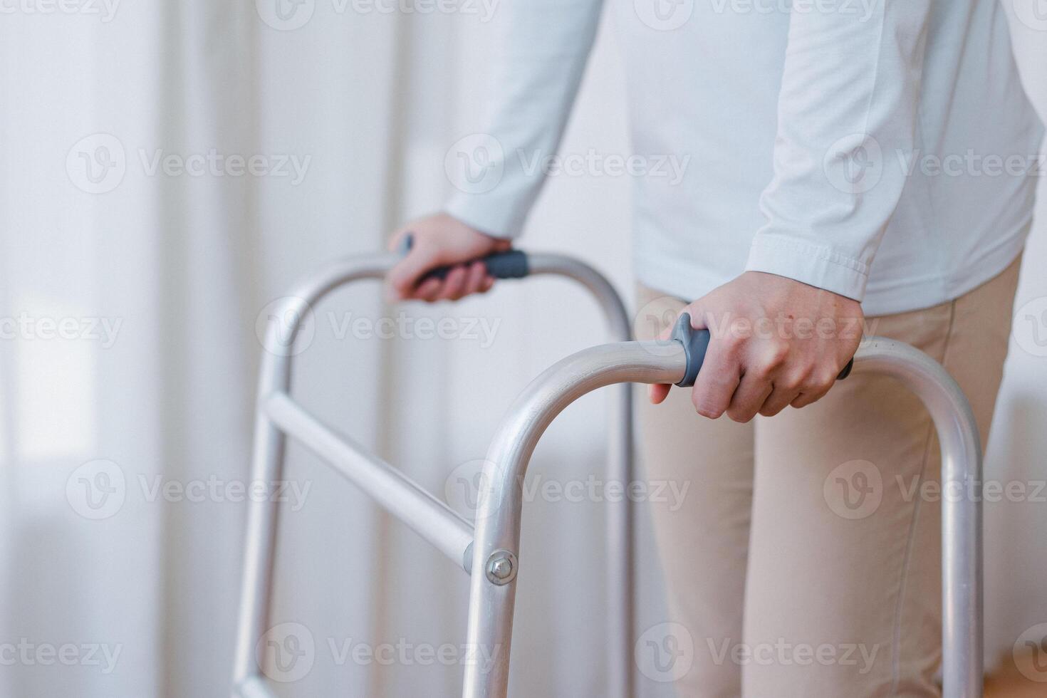 Cropped view of elderly man walking with frame at home, closeup. young male asian using medical equipment to move around his house. Disabled older person in need of professional help photo