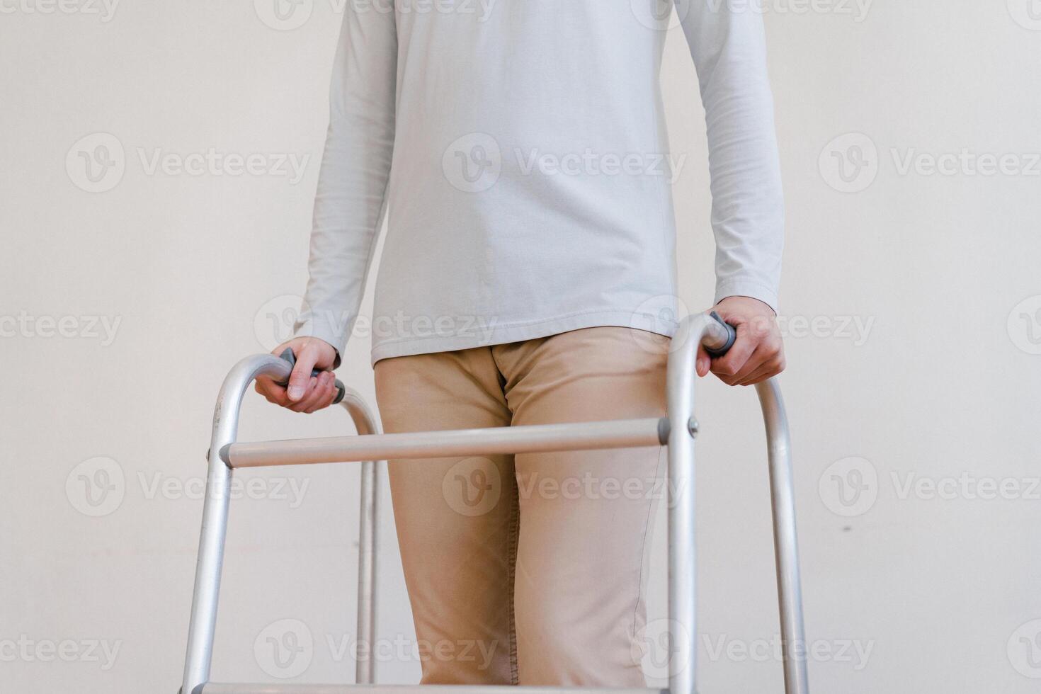 Cropped view of elderly man walking with frame at home, closeup. young male asian using medical equipment to move around his house. Disabled older person in need of professional help photo