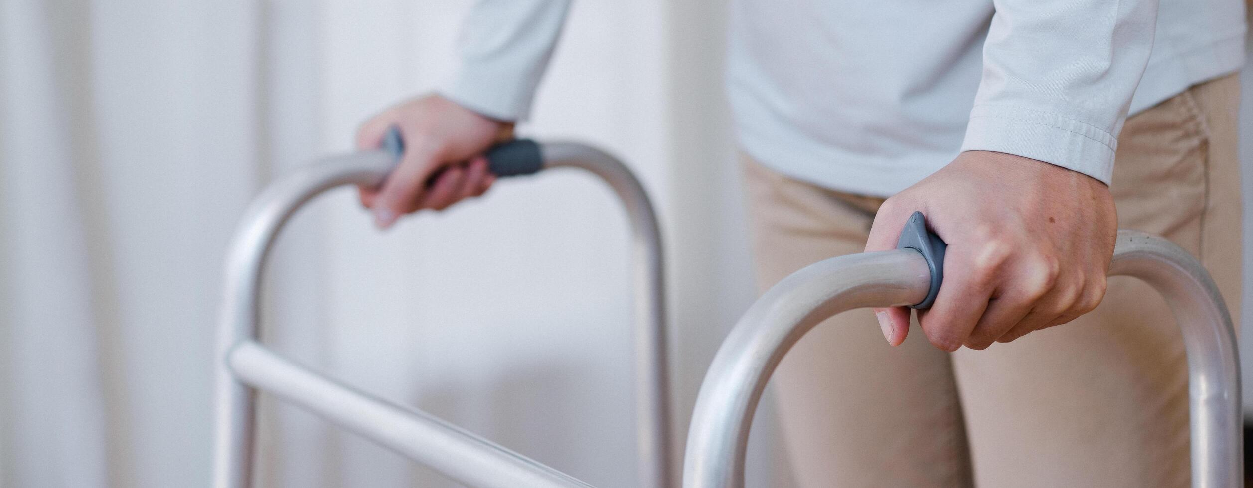 Cropped view of elderly man walking with frame at home, closeup. young male asian using medical equipment to move around his house. Disabled older person in need of professional help photo