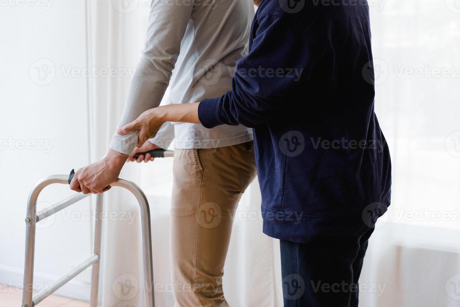 Cropped view of elderly man walking with frame at home, closeup. young male asian using medical equipment to move around his house. Disabled older person in need of professional help photo