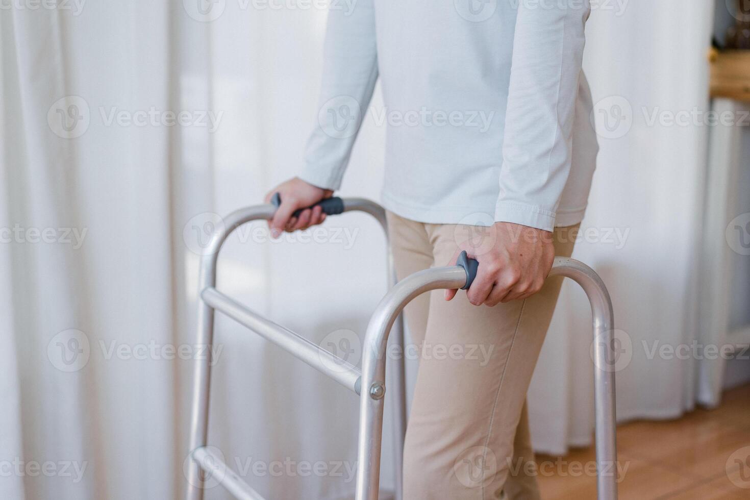 Cropped view of elderly man walking with frame at home, closeup. young male asian using medical equipment to move around his house. Disabled older person in need of professional help photo