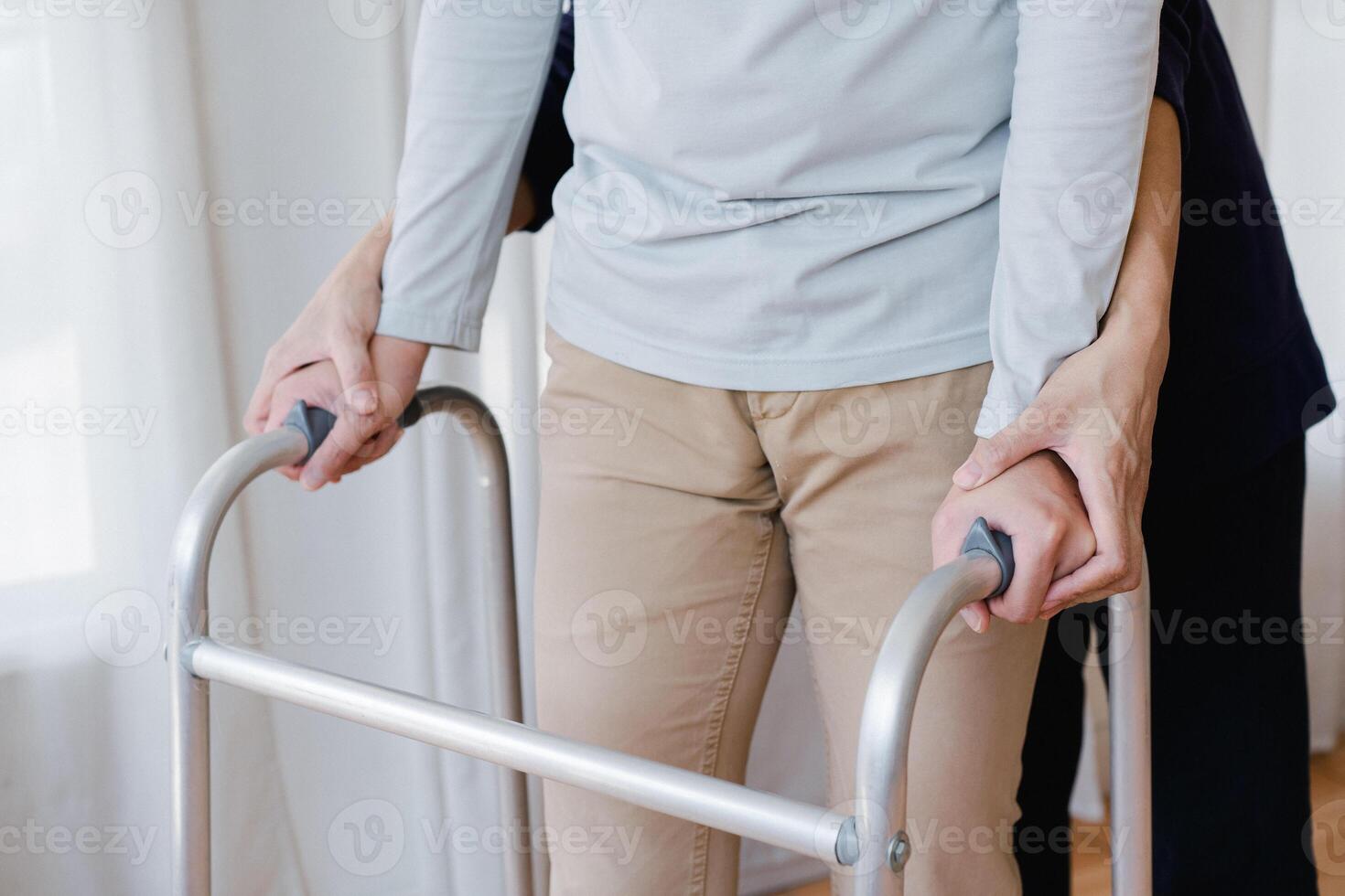 Cropped view of elderly man walking with frame at home, closeup. young male asian using medical equipment to move around his house. Disabled older person in need of professional help photo