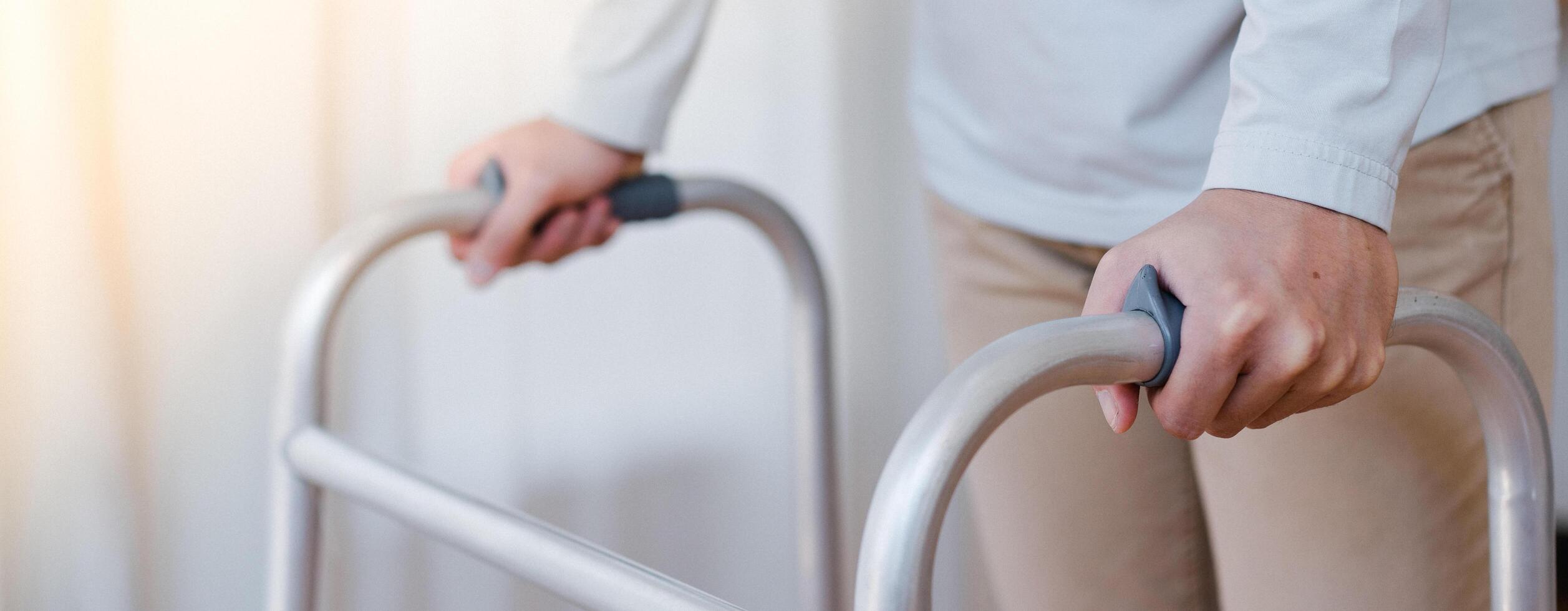 Cropped view of elderly man walking with frame at home, closeup. young male asian using medical equipment to move around his house. Disabled older person in need of professional help photo