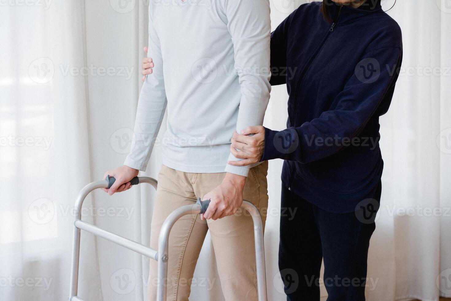 Cropped view of elderly man walking with frame at home, closeup. young male asian using medical equipment to move around his house. Disabled older person in need of professional help photo