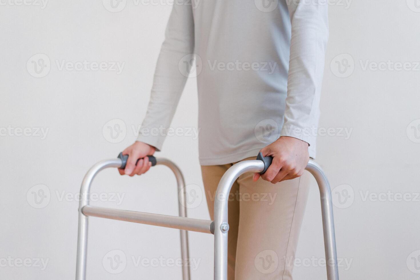Cropped view of elderly man walking with frame at home, closeup. young male asian using medical equipment to move around his house. Disabled older person in need of professional help photo