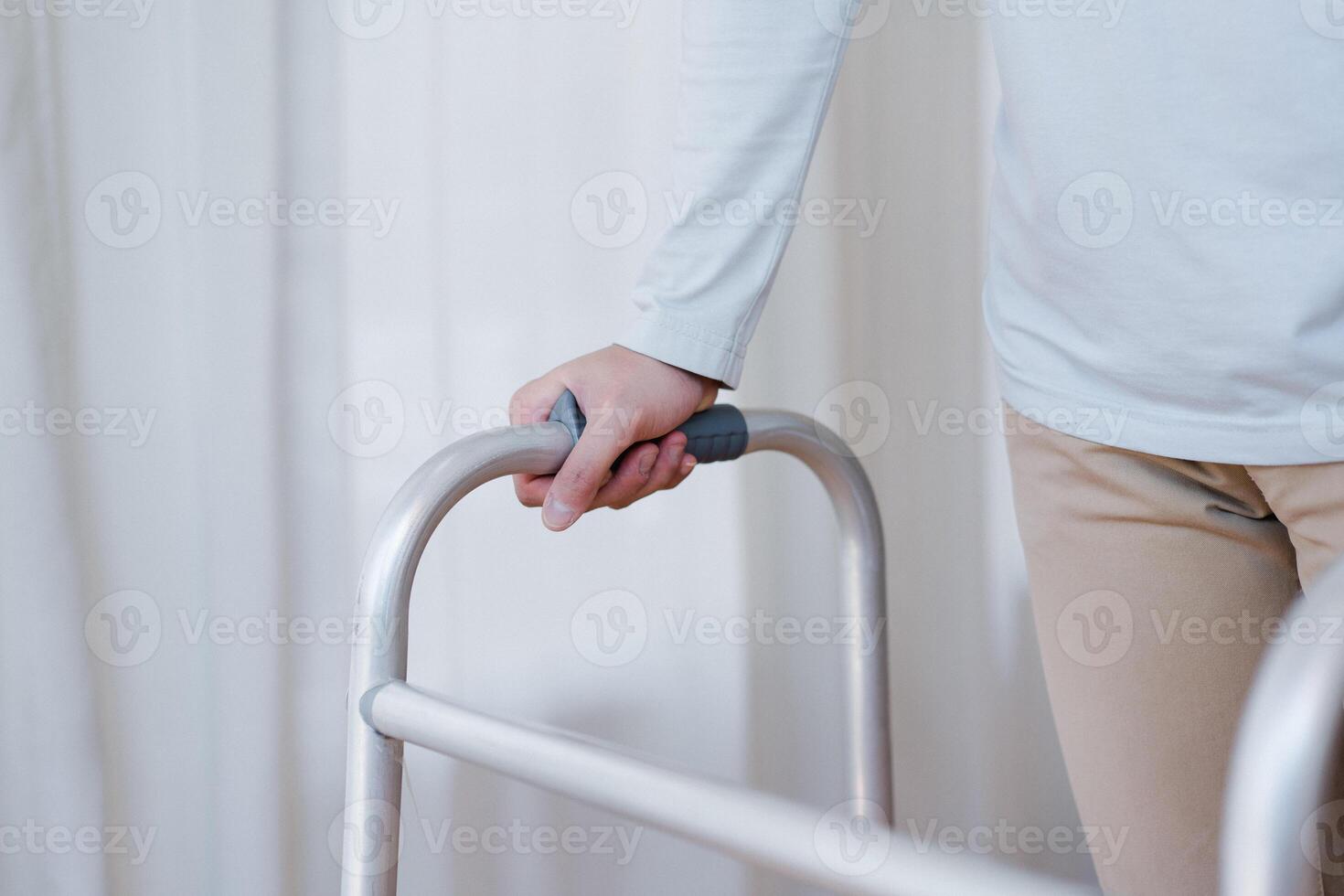 Cropped view of elderly man walking with frame at home, closeup. young male asian using medical equipment to move around his house. Disabled older person in need of professional help photo