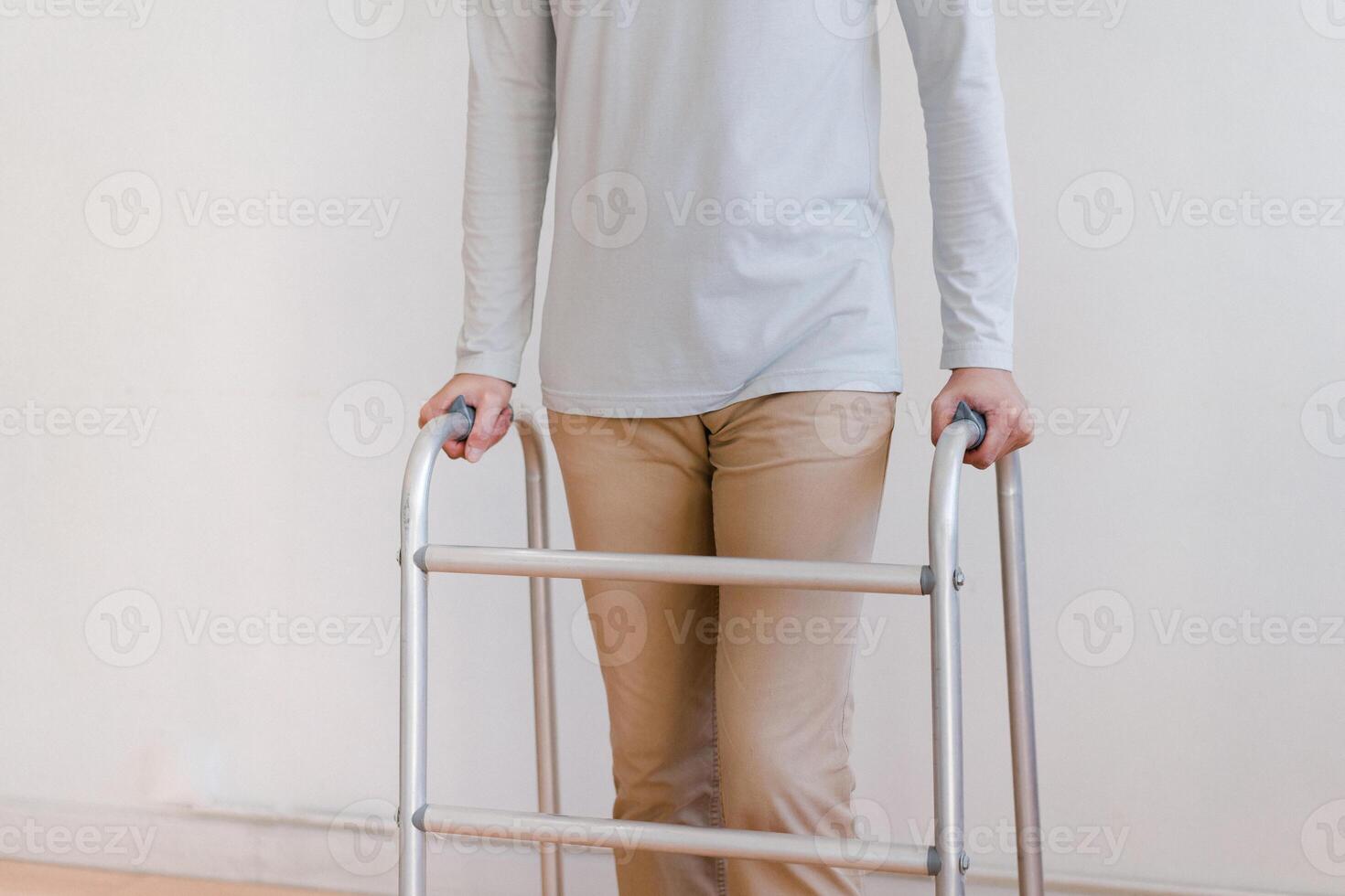 Cropped view of elderly man walking with frame at home, closeup. young male asian using medical equipment to move around his house. Disabled older person in need of professional help photo