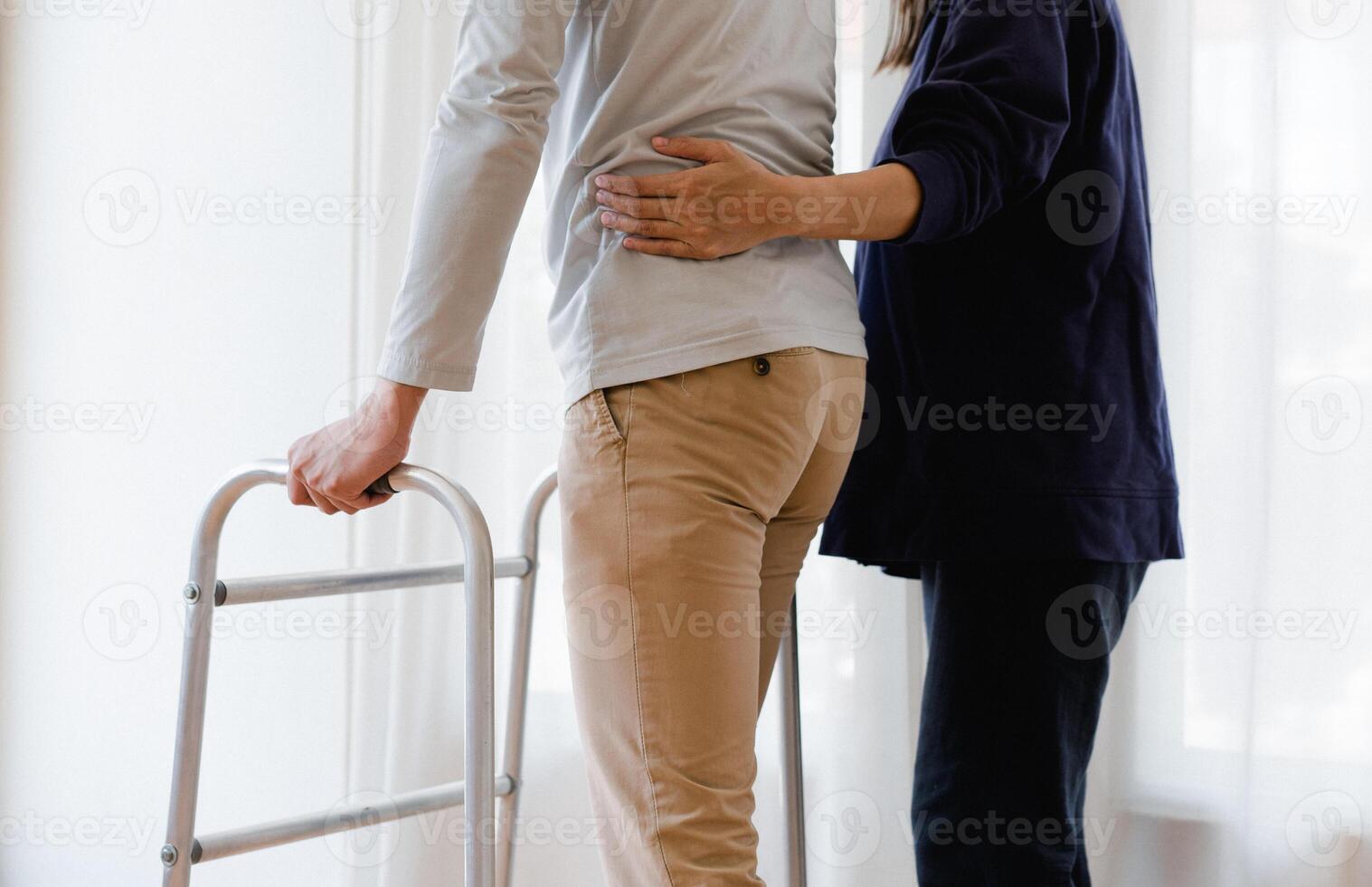 Cropped view of elderly man walking with frame at home, closeup. young male asian using medical equipment to move around his house. Disabled older person in need of professional help photo