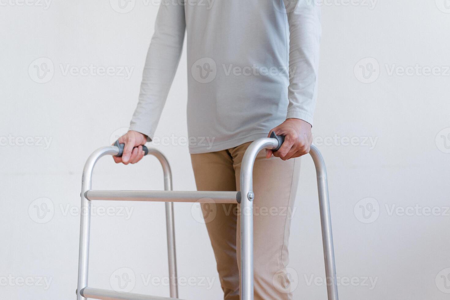 Cropped view of elderly man walking with frame at home, closeup. young male asian using medical equipment to move around his house. Disabled older person in need of professional help photo
