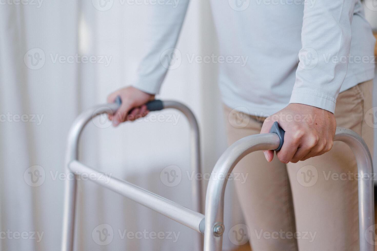 Cropped view of elderly man walking with frame at home, closeup. young male asian using medical equipment to move around his house. Disabled older person in need of professional help photo
